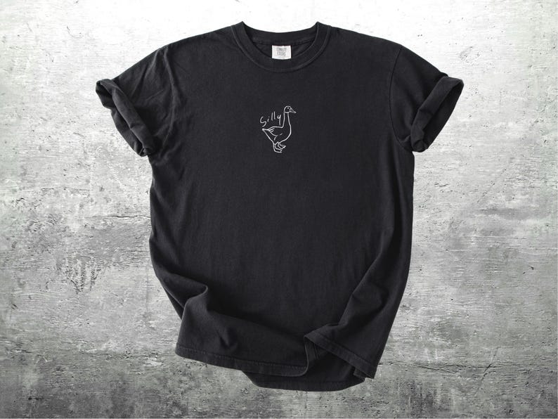 May include: Black t-shirt with a white outline of a goose and the word "Silly" above it.