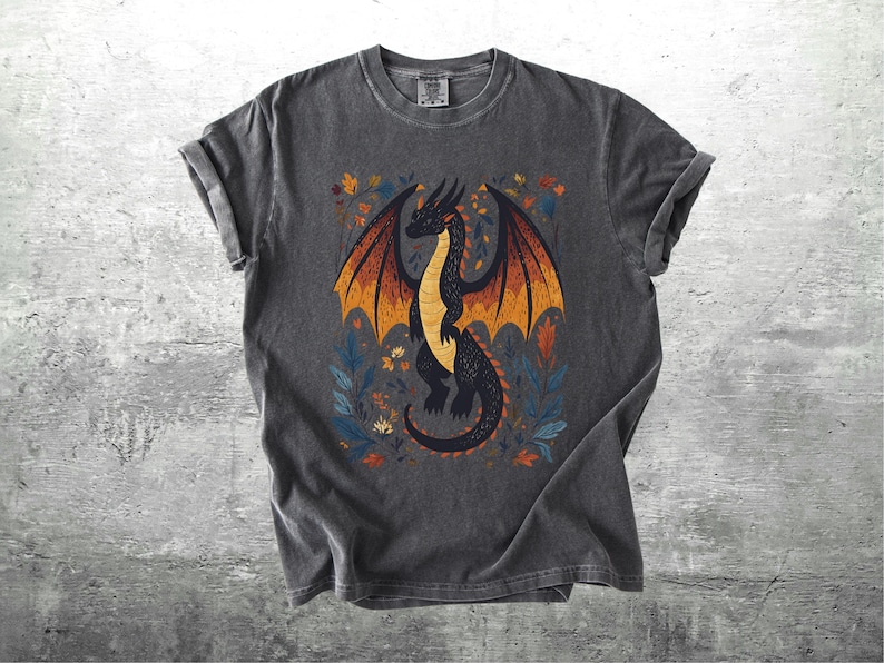 May include: A dark gray t-shirt with a black dragon illustration. The dragon has orange and yellow wings and is surrounded by floral designs in shades of blue, orange, and yellow.