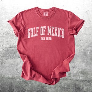 May include: Red t-shirt with white text that reads "GULF OF MEXICO EST 1550".
