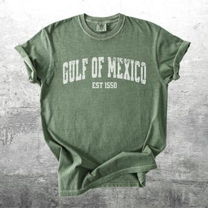 May include: A green t-shirt with the text "GULF OF MEXICO EST 1550" printed in white on the front.