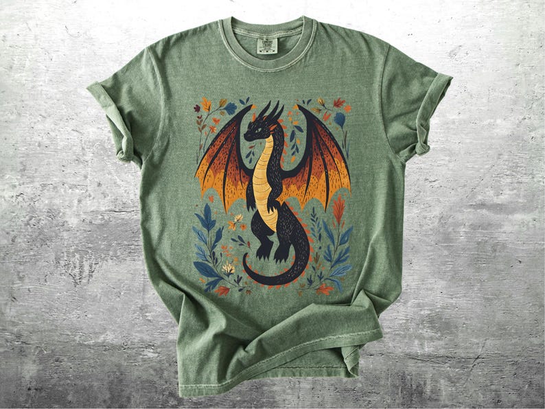 May include: A green t-shirt with a black dragon illustration surrounded by colorful flowers. The dragon has orange wings and is facing to the right.