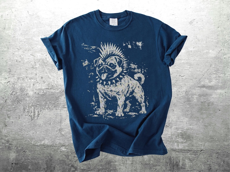 May include: A navy blue t-shirt featuring a distressed graphic of a punk rock pug dog with a mohawk and studded collar. The dog is in a standing pose, with its tongue sticking out. The shirt has rolled-up sleeves.