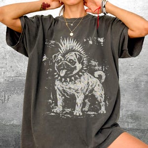 May include: Dark gray t-shirt featuring a punk rock pug graphic. The dog has a mohawk and spiked collar. The shirt is oversized and has short sleeves.