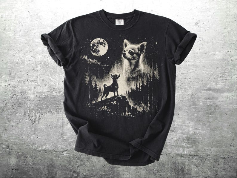 May include: Black t-shirt featuring a graphic of a Chihuahua dog under a full moon in a forest setting. The design includes a large dog head and a smaller dog standing on a hill. The artwork is in shades of white and tan.