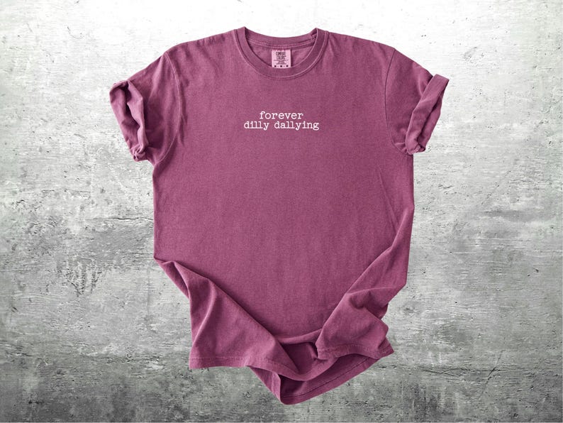 May include: A maroon t-shirt with the text "forever dilly dallying" printed in white on the front.