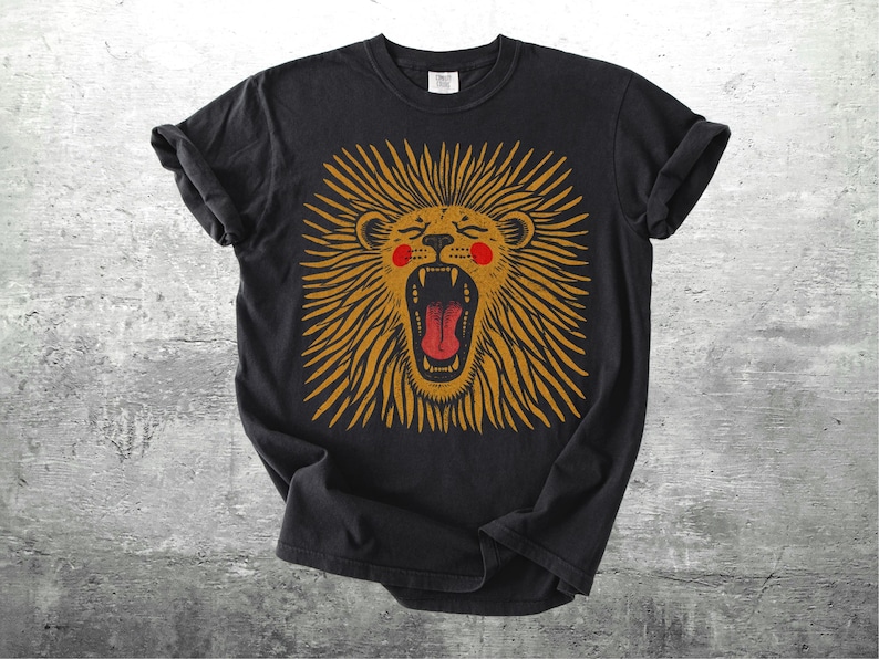 May include: Black t-shirt with a roaring lion design. The lion has a golden mane, red mouth, and pink cheeks. The design is centered on the shirt, with the sleeves rolled up. The shirt is made of a soft material.