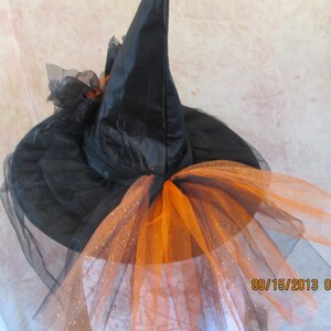 May include: Black witch hat with a black tulle veil and orange tulle trim. The hat has a pointed crown and a wide brim.