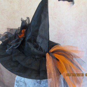 May include: Black witch hat with orange and black tulle and a black veil. The hat has a pointed crown and a wide brim.