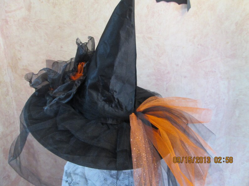 May include: Black witch hat with orange and black tulle and a black veil. The hat has a pointed crown and a wide brim.