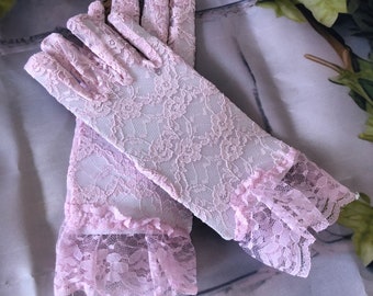 May include: A pair of pink lace gloves with a ruffled edge. The gloves are made of delicate, sheer fabric and have a floral pattern.