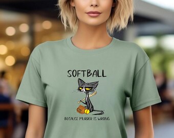 May include: Sage green t-shirt with the word "SOFTBALL" above a cartoon cat holding a bat and ball. The text "BECAUSE MURDER IS WRONG" is below the cat illustration. The shirt is a casual, short-sleeved style.