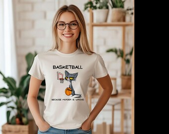 Könnte beinhalten: Weißes T-Shirt mit einer Comic-Katze, die Basketball spielt. Der Text auf dem Shirt lautet "Basketball because murder is wrong."