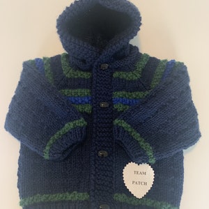 May include: A navy blue knitted hooded cardigan with green and blue stripes and a white heart-shaped tag that says "TEAM PATCH".