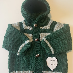 May include: Green and gray striped knitted baby cardigan with a hood and football buttons. The cardigan has a white heart-shaped tag that says "TEAM PATCH".