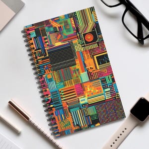 Könnte beinhalten: Ein spiralgebundenes Notizbuch mit einem farbenfrohen geometrischen Muster. Der Einband zeigt eine Vielzahl von Formen und Farben, darunter Orange, Gelb, Grün, Blau und Rot. Das Notizbuch ist perfekt zum Notieren, Journalisieren oder Skizzieren.