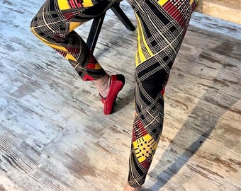 Puede incluir: Pantalones ajustados con un llamativo estampado geométrico en negro, amarillo y rojo. Los pantalones presentan un diseño de cuadros y se combinan con mocasines rojos. El estilo general es llamativo y moderno.