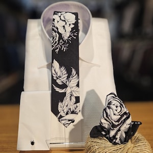 May include: A white dress shirt with a black and white floral patterned tie and a matching pocket square.