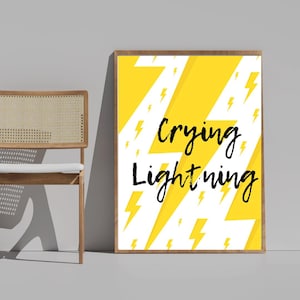 Puede incluir: Una impresión artística enmarcada con las palabras "Crying Lightning" en escritura negra. El fondo es amarillo con un patrón de rayos blancos y amarillos. El marco es de color marrón claro.