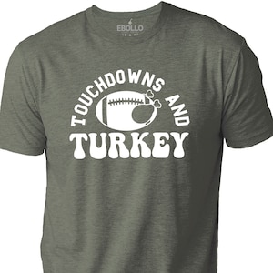 Könnte beinhalten: Ein grünes T-Shirt mit einer weißen Grafik eines Fußballs und eines Truthahns mit dem Text "Touchdowns and Turkey" in einer Retro-Schrift.