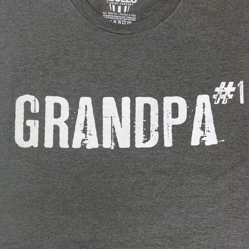 May include: Gray t-shirt with white text that reads "GRANDPA #1".