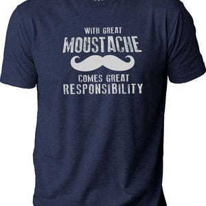 May include: Navy blue t-shirt with the text "WITH GREAT MOUSTACHE COMES GREAT RESPONSIBILITY" in white, along with a white mustache graphic. The shirt has short sleeves and a crew neck.