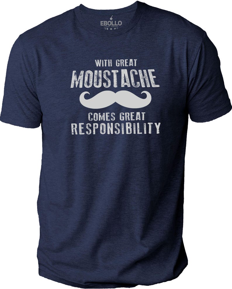 May include: Navy blue t-shirt with the text "WITH GREAT MOUSTACHE COMES GREAT RESPONSIBILITY" in white, along with a white mustache graphic. The shirt has short sleeves and a crew neck.