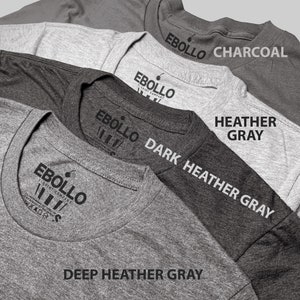 May include: A selection of grey t-shirts, each with the "EBOLLO T-SHIRT COMPANY" logo. The shirts are in shades of grey, such as Charcoal, Heather Gray, Dark Heather Gray, and Deep Heather Gray. Sizes are indicated on the shirts.