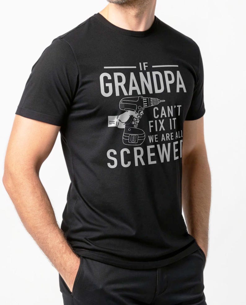 Puede incluir: Camiseta negra con el texto "IF GRANDPA CAN'T FIX IT WE ARE ALL SCREWED" en gris. Tambi&eacute;n hay una ilustraci&oacute;n gris de un taladro. La camiseta es de manga corta.