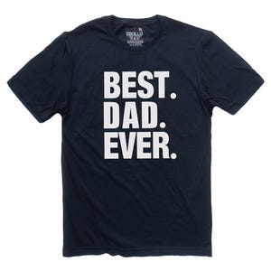 Puede incluir: Camiseta azul marino con el texto blanco "BEST. DAD. EVER." en letras gruesas. La camiseta tiene mangas cortas y cuello redondo. El nombre de la marca "EBBOLLO" est&aacute; impreso en la parte superior trasera de la camiseta.