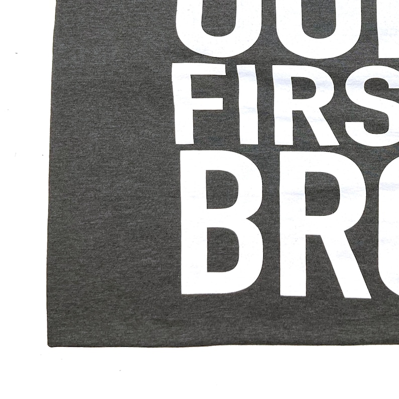 May include: A dark gray t-shirt with the text "You're my first bro" printed in white.