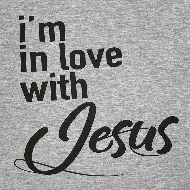 May include: Gray t-shirt with black text that reads "i'm in love with Jesus".