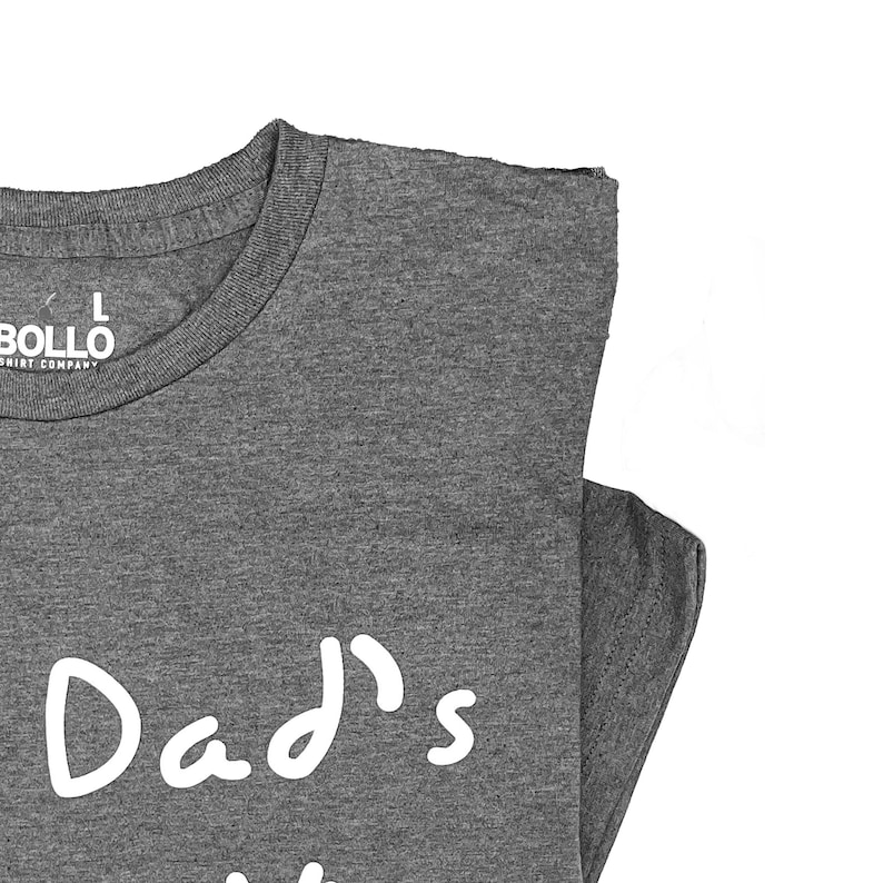 Peut inclure: Un t-shirt gris chin&eacute; avec le texte "Dad's" &eacute;crit en blanc sur le devant.
