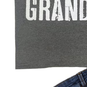 May include: A gray t-shirt with the word "GRAND" printed in white on the front.