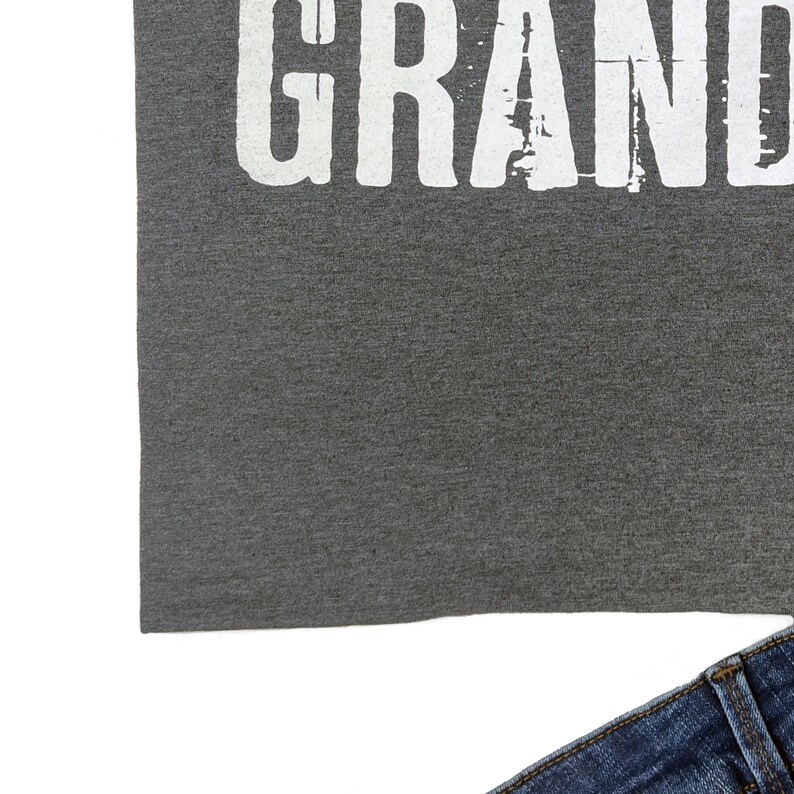 May include: A gray t-shirt with the word "GRAND" printed in white on the front.