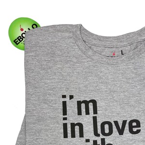 May include: Gray t-shirt with the text "i'm in love with the" printed on the front.