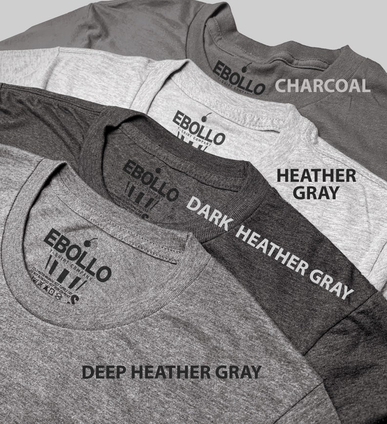 May include: Four t-shirts in different shades of gray, from lightest to darkest: Heather Gray, Dark Heather Gray, Deep Heather Gray, and Charcoal. Each shirt has a label with the text "EBOLLO T-SHIRT COMPANY" printed on it.
