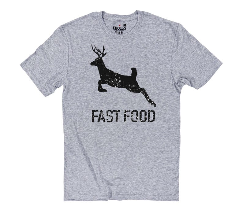May include: A grey t-shirt with a black deer silhouette leaping, speckled with white dots. The words "FAST FOOD" are printed below in a distressed font. The shirt has a crew neck and short sleeves.