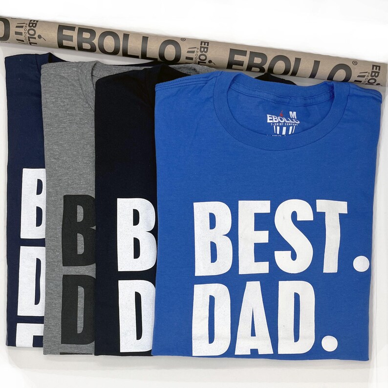 Puede incluir: Cinco camisetas en azul marino, gris, negro y azul. La camiseta azul tiene el texto "BEST DAD." en letras blancas grandes. Las camisetas son de la empresa "EBOLIO" T-shirt.