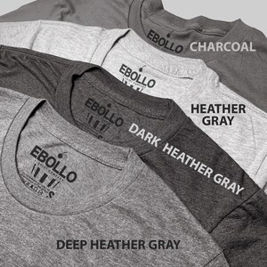 Peut inclure: Quatre t-shirts dans diff&eacute;rentes nuances de gris, du plus clair au plus fonc&eacute;. Les t-shirts sont empil&eacute;s les uns sur les autres, le t-shirt gris le plus fonc&eacute; en bas. Chaque t-shirt porte une &eacute;tiquette avec le texte "EBOLLO T-SHIRT COMPANY" et la couleur du t-shirt. Les couleurs sont : Gris chin&eacute; fonc&eacute;, Gris chin&eacute; fonc&eacute;, Gris chin&eacute; et Anthracite.