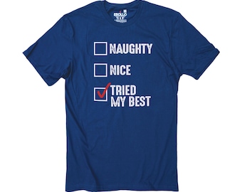 May include: A navy blue t-shirt with the text "NAUGHTY", "NICE", and "TRIED MY BEST" in white. The "TRIED MY BEST" option is checked with a red checkmark. The shirt has a crew neck and short sleeves.