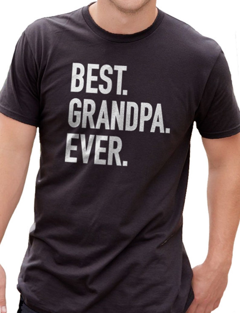 May include: Dark gray t-shirt with the text "BEST. GRANDPA. EVER." printed in white. The shirt has a crew neck and short sleeves. The text is centered on the front of the shirt.