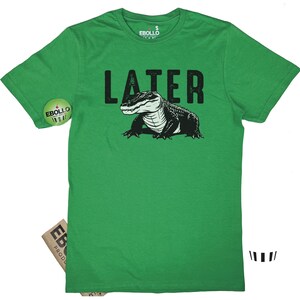 Op de afbeelding: Groen T-shirt met een zwarte alligator-afbeelding en het woord "LATER" in witte tekst.