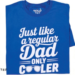 May include: Royal blue t-shirt with the text "Just like a regular Dad ONLY COOLER" in white. The shirt features a pair of sunglasses below the text. The brand name "EBOLLO" is printed on the collar.