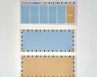 May include: Two blank notepads with blue and orange borders. The top notepad has a weekly planner layout with the days of the week labeled. The bottom notepad is a blank rectangle.