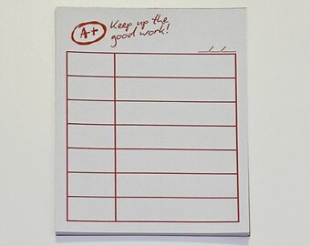 May include: A white notepad with a red border and lines for writing. The top left corner has a red circle with "A+" inside. Above the lines, the text reads "Keep up the good work!"