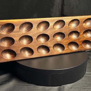 Pode incluir: Uma bandeja de servir de madeira com 18 reentrâncias ovais. A bandeja é feita de madeira castanha escura e está rotulada como "Handmade in the USA". É projetada para conter itens pequenos.