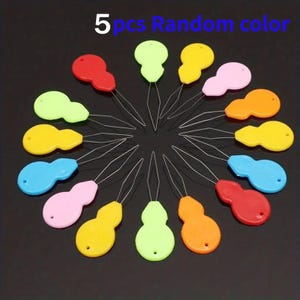 May include: A collection of 15 colorful plastic needle threaders in various colors, including red, yellow, pink, green, orange, and blue. Each threader has a wire loop for easy threading. The text "5 pcs Random color" is visible.