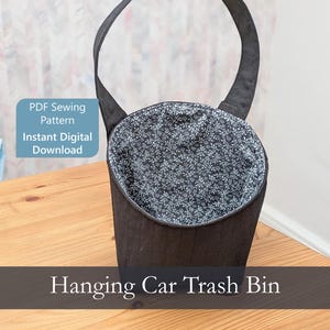 May include: A black fabric hanging car trash bin with a long strap and a black and white floral interior lining. The image includes the text PDF Sewing Pattern Instant Digital Download and the text Hanging Car Trash Bin.