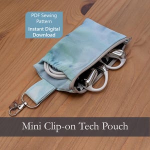 May include: A mini clip-on tech pouch with a light blue and white watercolor-style print. The pouch features a silver metal swivel clasp, a zippered opening, and contains white charging cables and white earbuds. Text reads: PDF Sewing Pattern Instant Digital Download and Mini Clip-on Tech Pouch.