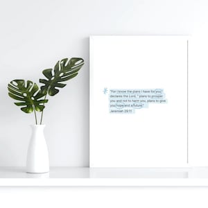 May include: A white framed print with a blue background and white text. The text reads "For I know the plans I have for you declares the Lord, " plans to prosper you and not to harm you, plans to give you hope and a future" Jeremiah 29:11. The print is sitting on a white shelf with a white vase and green plant.